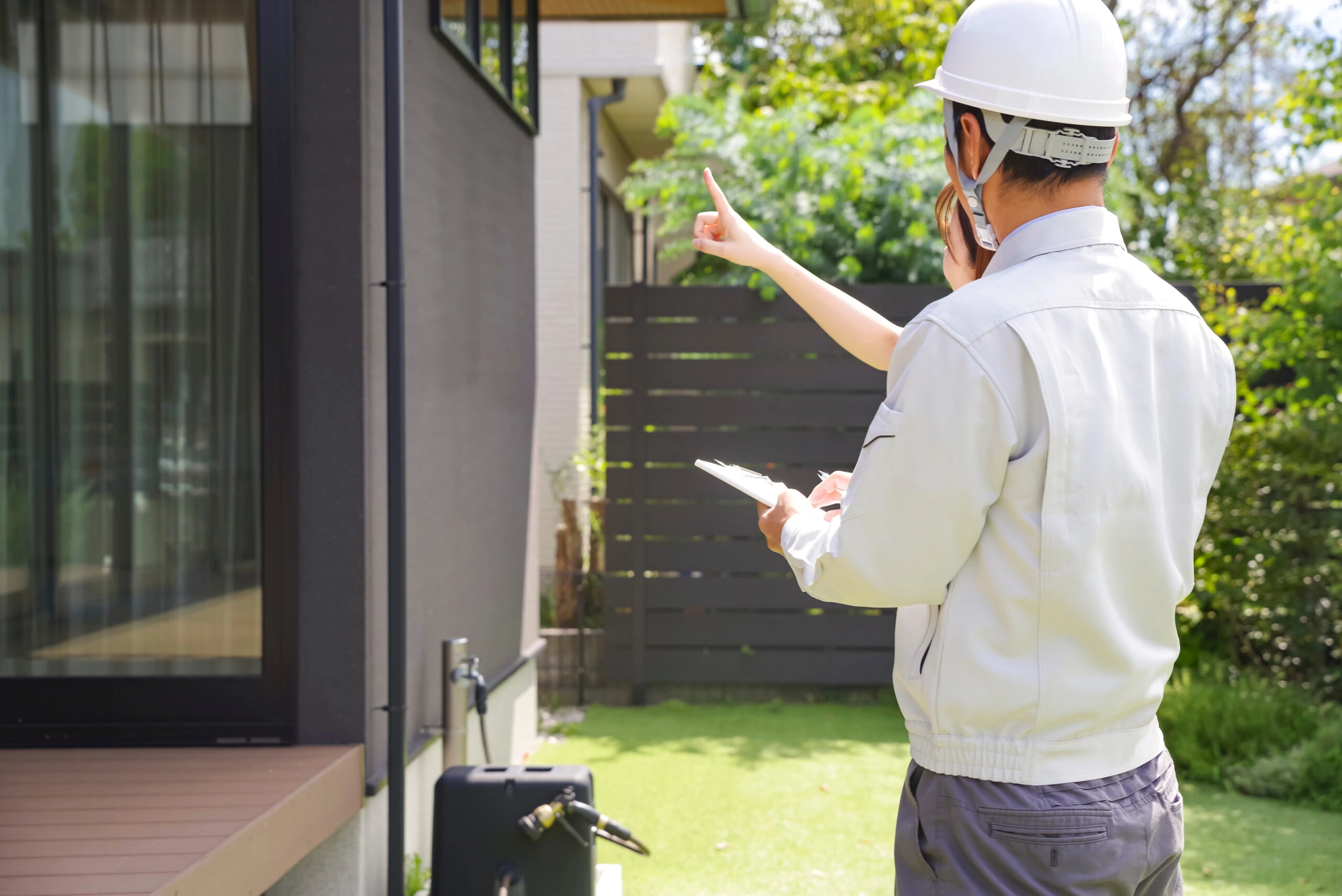 住宅の外壁を確認する作業員