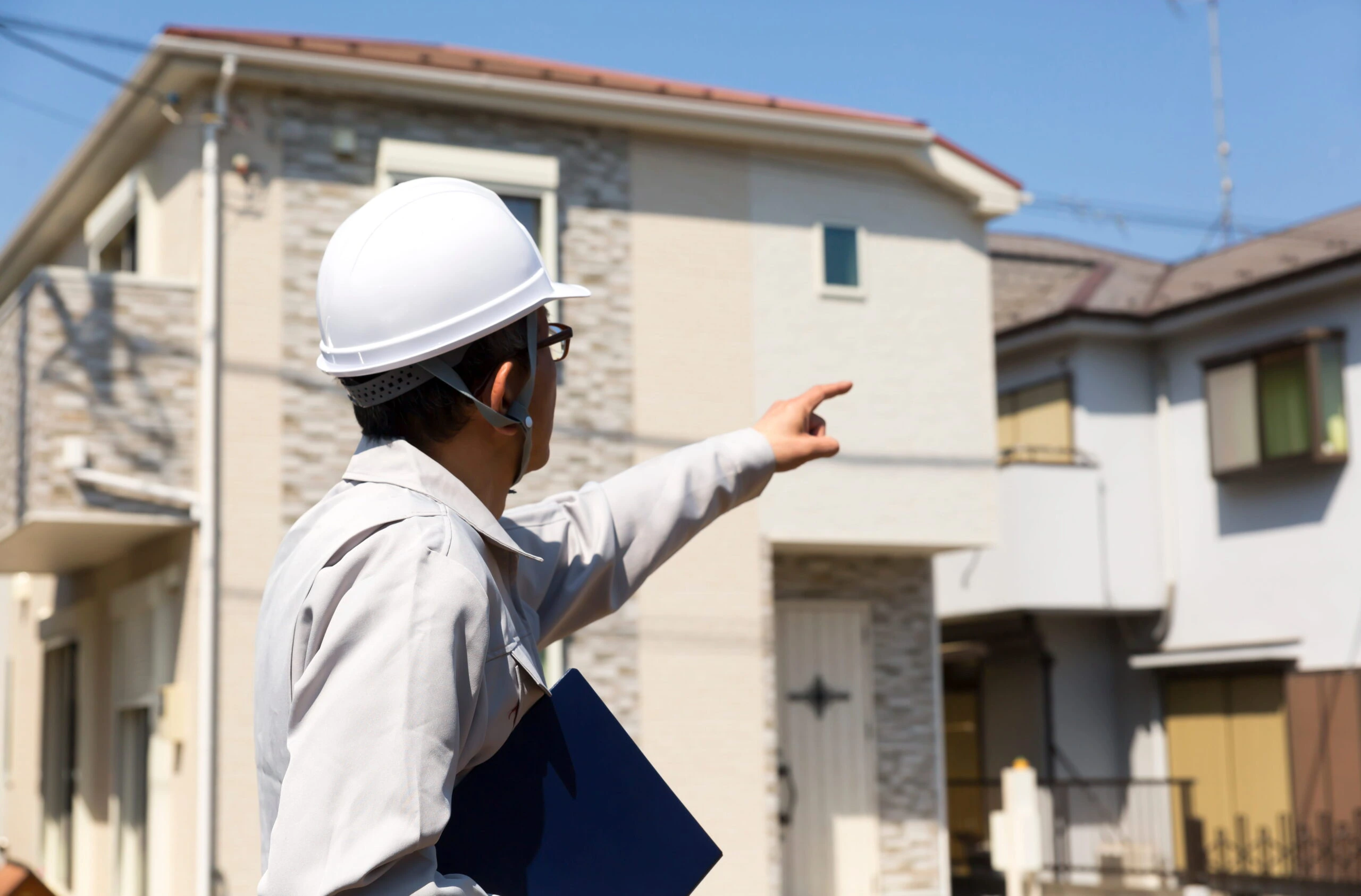 住宅の外壁を確認する作業員
