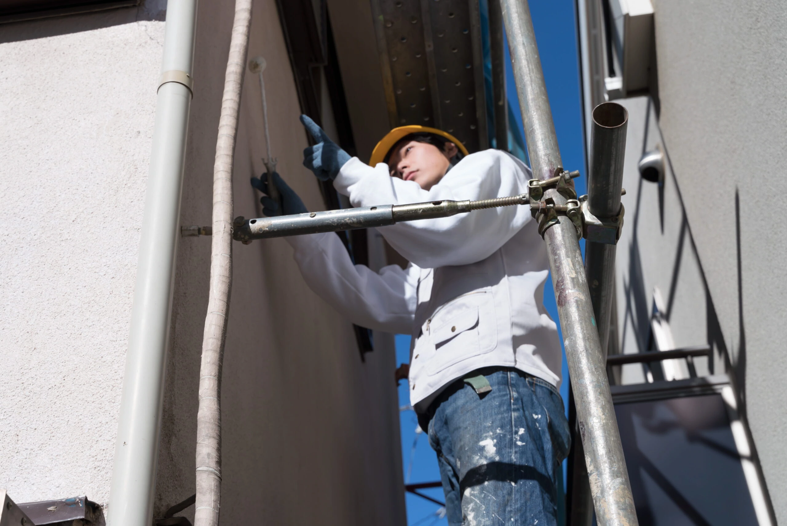 足場で縦樋の施工を行う作業員